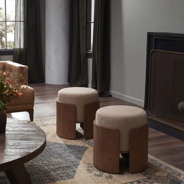 Two round upholstered ottomans with curved wooden side supports in a styled living room setting.