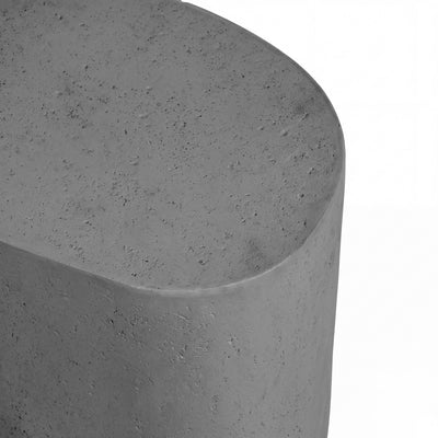Close-up of a modern gray concrete pouf stool with a textured finish and rounded top, set against a plain white background.
