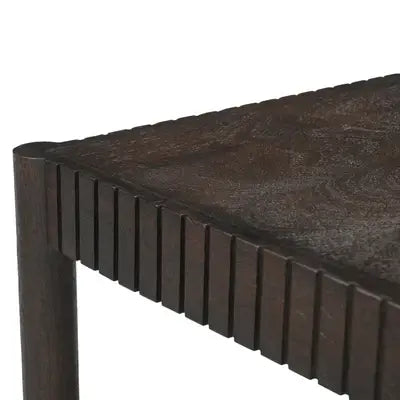 Close-up of a dark brown wooden table corner showing the slatted apron and tabletop grain against a white background.