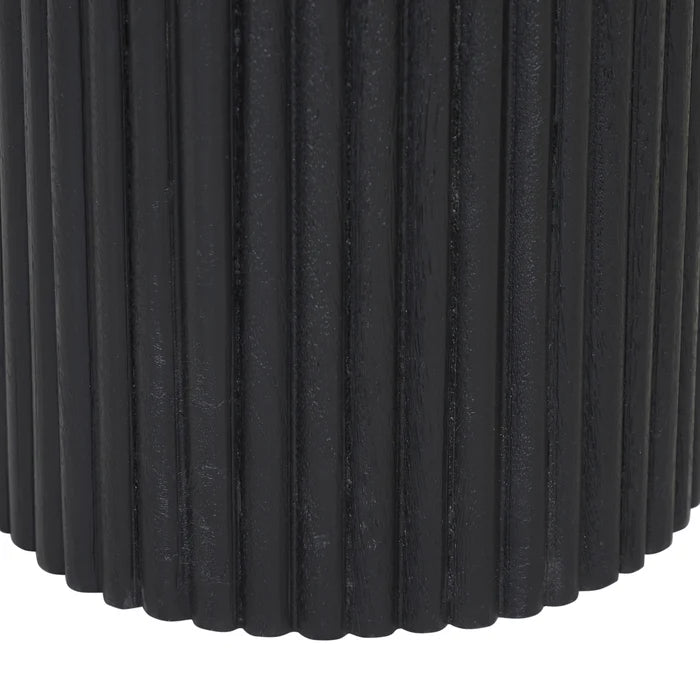 Close-up of a black cylindrical ribbed side table or stool with vertical fluted ridges, shown against a white background.