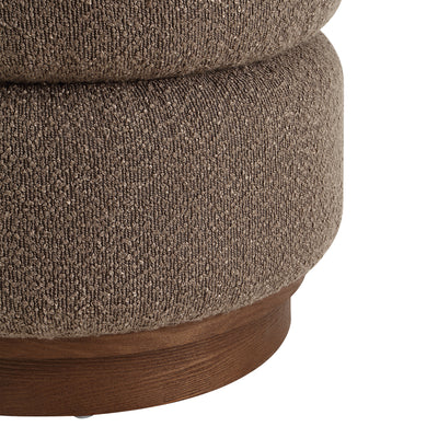 Close-up of a round upholstered ottoman or stool with textured taupe-brown fabric and a round wooden base, shown on a white background.